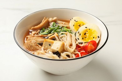 Photo of Bowl of delicious ramen on white marble table. Noodle soup