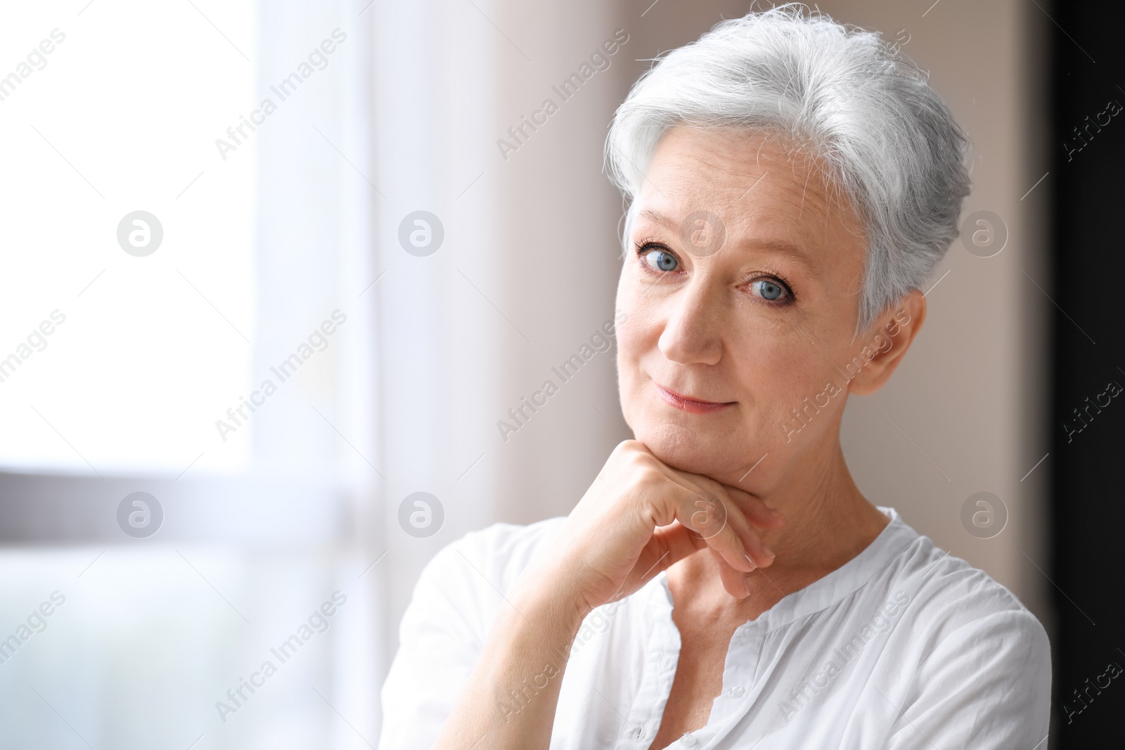 Photo of Happy mature woman near window indoors, space for text. Smart aging