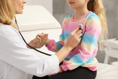 Photo of Pediatrician examining little patient with stethoscope in clinic, closeup