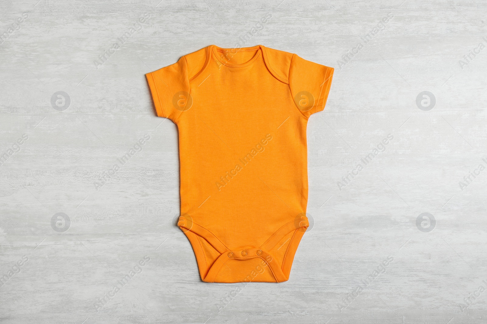 Photo of Baby bodysuit on wooden background, top view