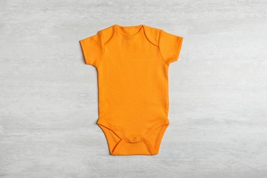 Photo of Baby bodysuit on wooden background, top view