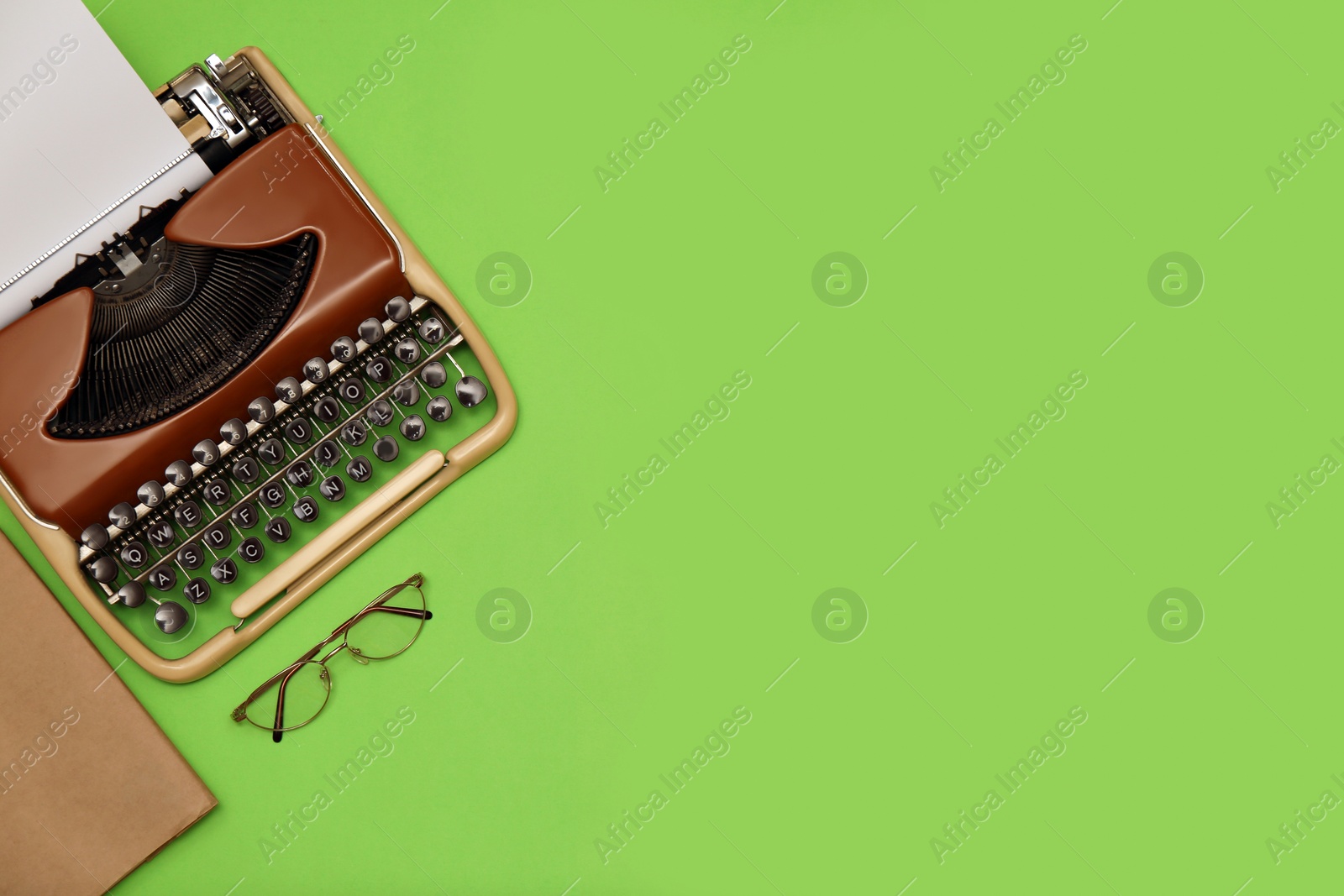 Photo of Vintage typewriter with sheet of paper and glasses on green background, flat lay. Space for text