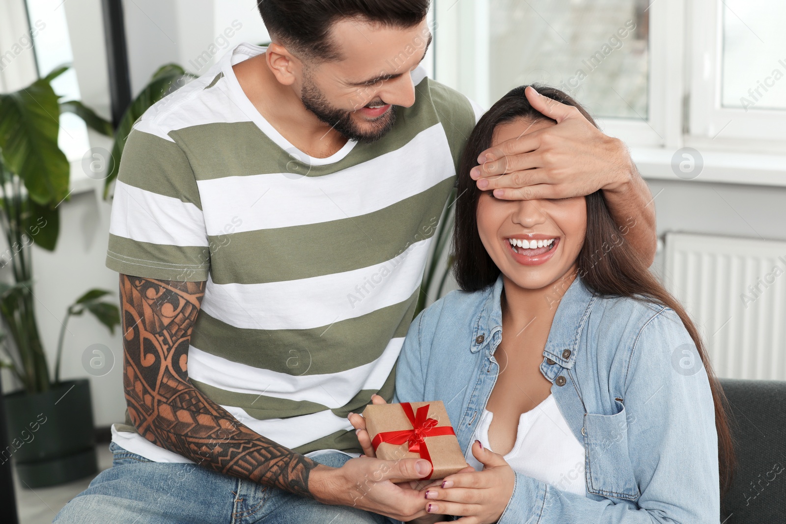 Photo of Man presenting gift to his girlfriend at home