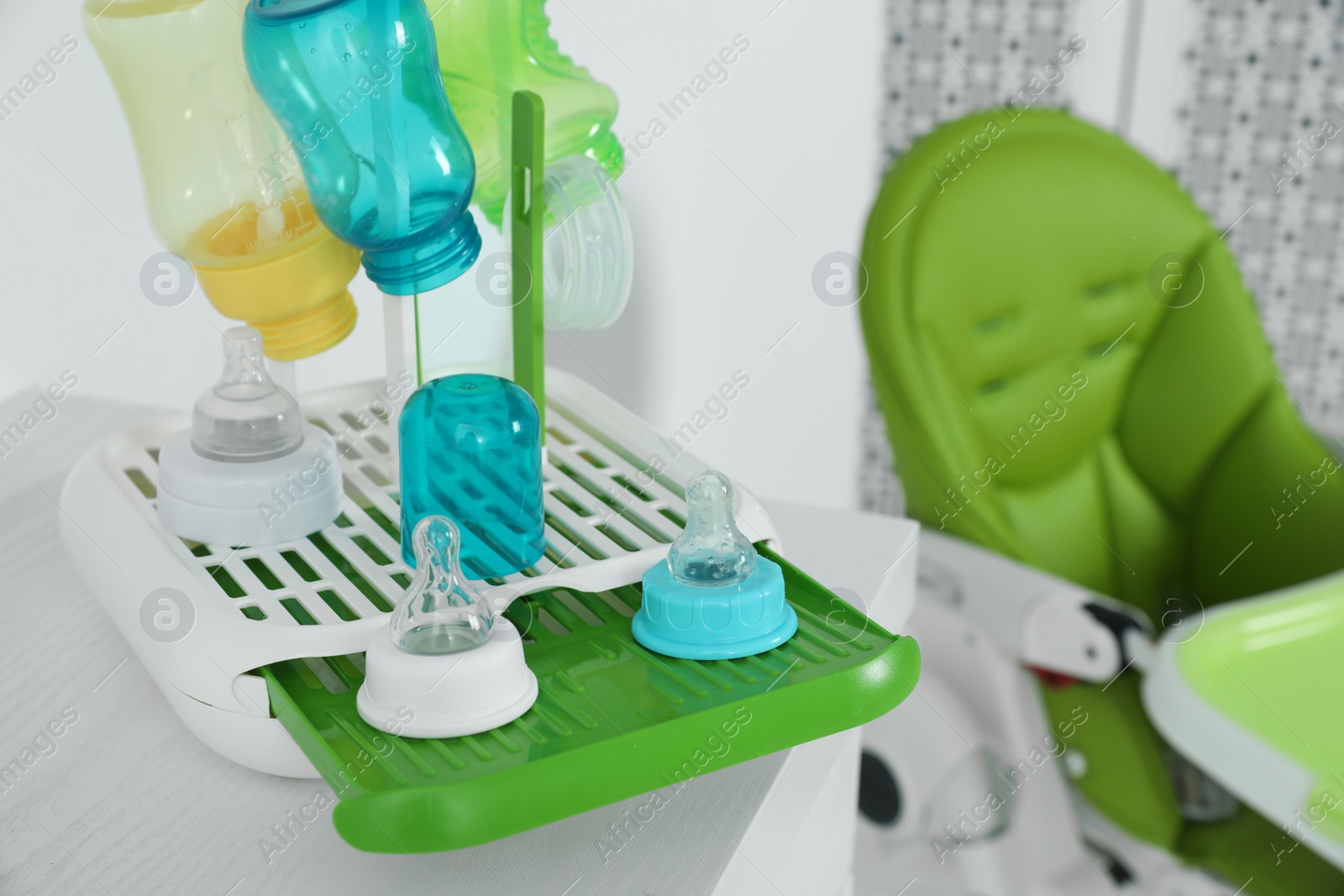 Photo of Dryer with baby bottles and nipples after sterilization on white table indoors