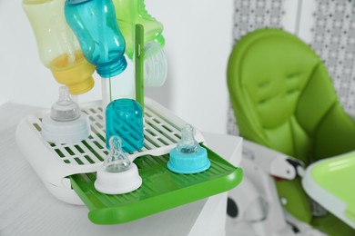 Photo of Dryer with baby bottles and nipples after sterilization on white table indoors