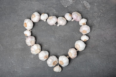 Photo of Heart made of fresh garlic bulbs on gray background, top view