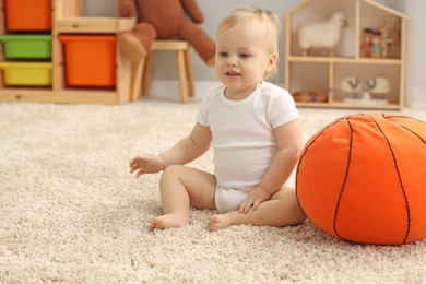 Photo of Children toys. Cute little boy and soft toy ball on rug at home, space for text