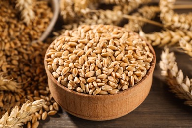 Photo of Wheat grains with spikelets on wooden table, closeup