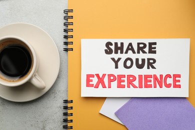 Photo of Share Your Experience. Notebook with paper notes and coffee on light grey table, flat lay