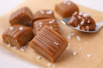 Photo of Delicious salted caramel on parchment paper, closeup