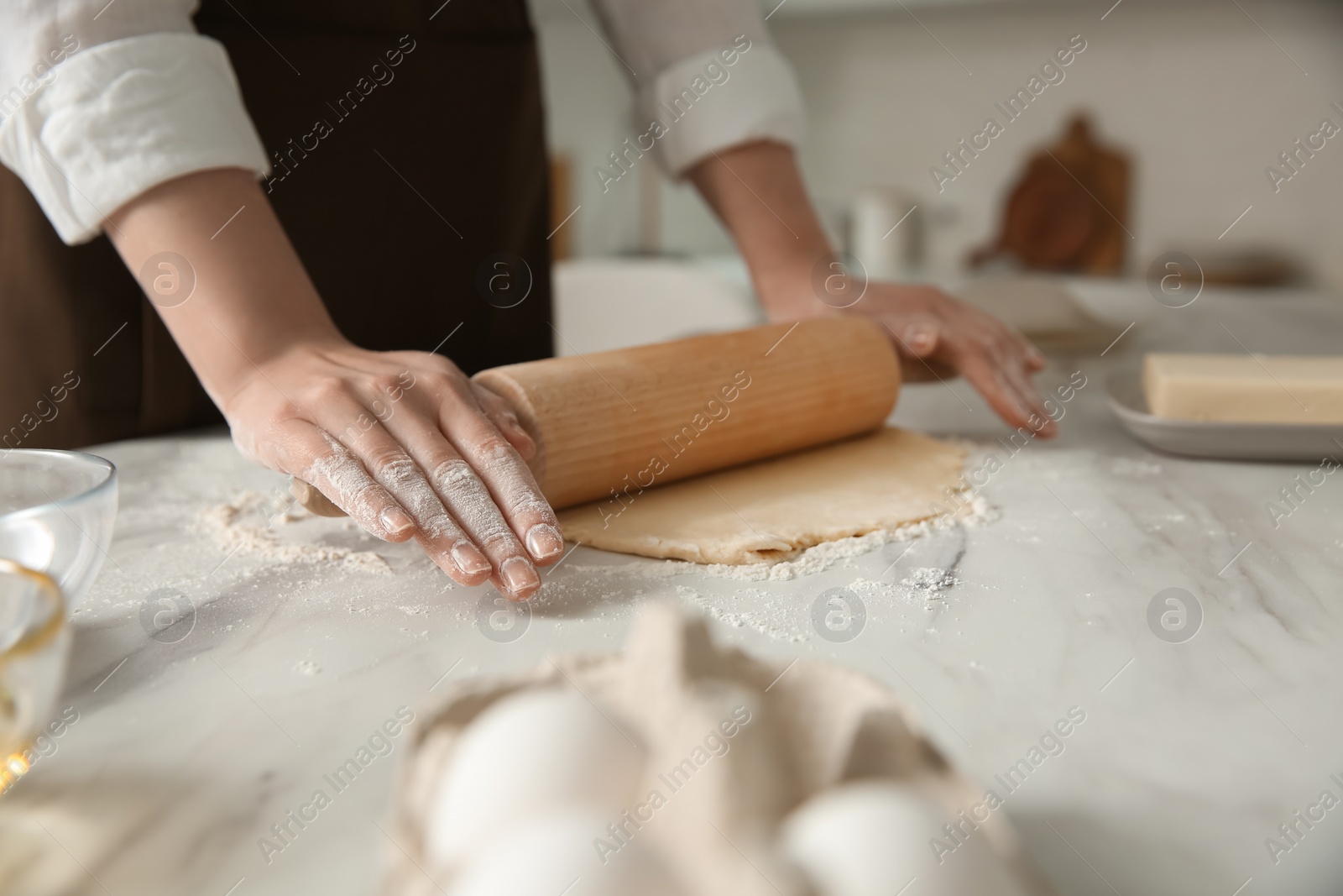 Photo of Woman rolling dough at table in kitchen, closeup
