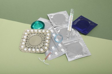 Photo of Contraceptive pills, condoms, intrauterine device and thermometer on color background. Choice of birth control method