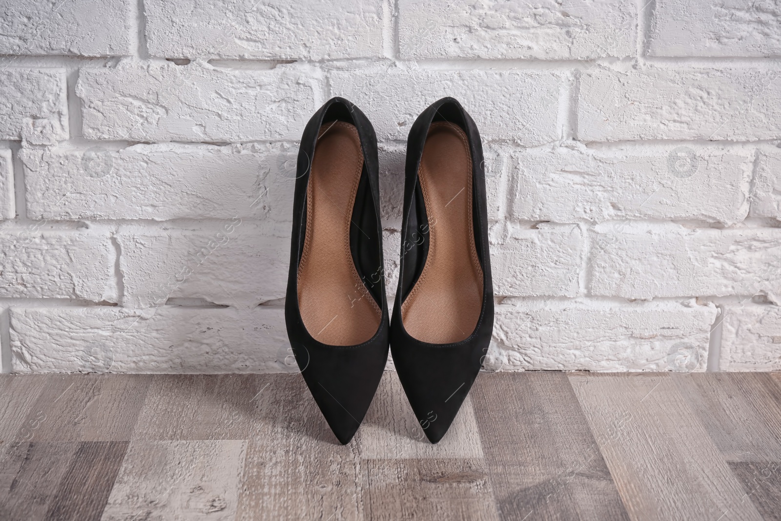 Photo of Pair of female shoes on floor against brick wall