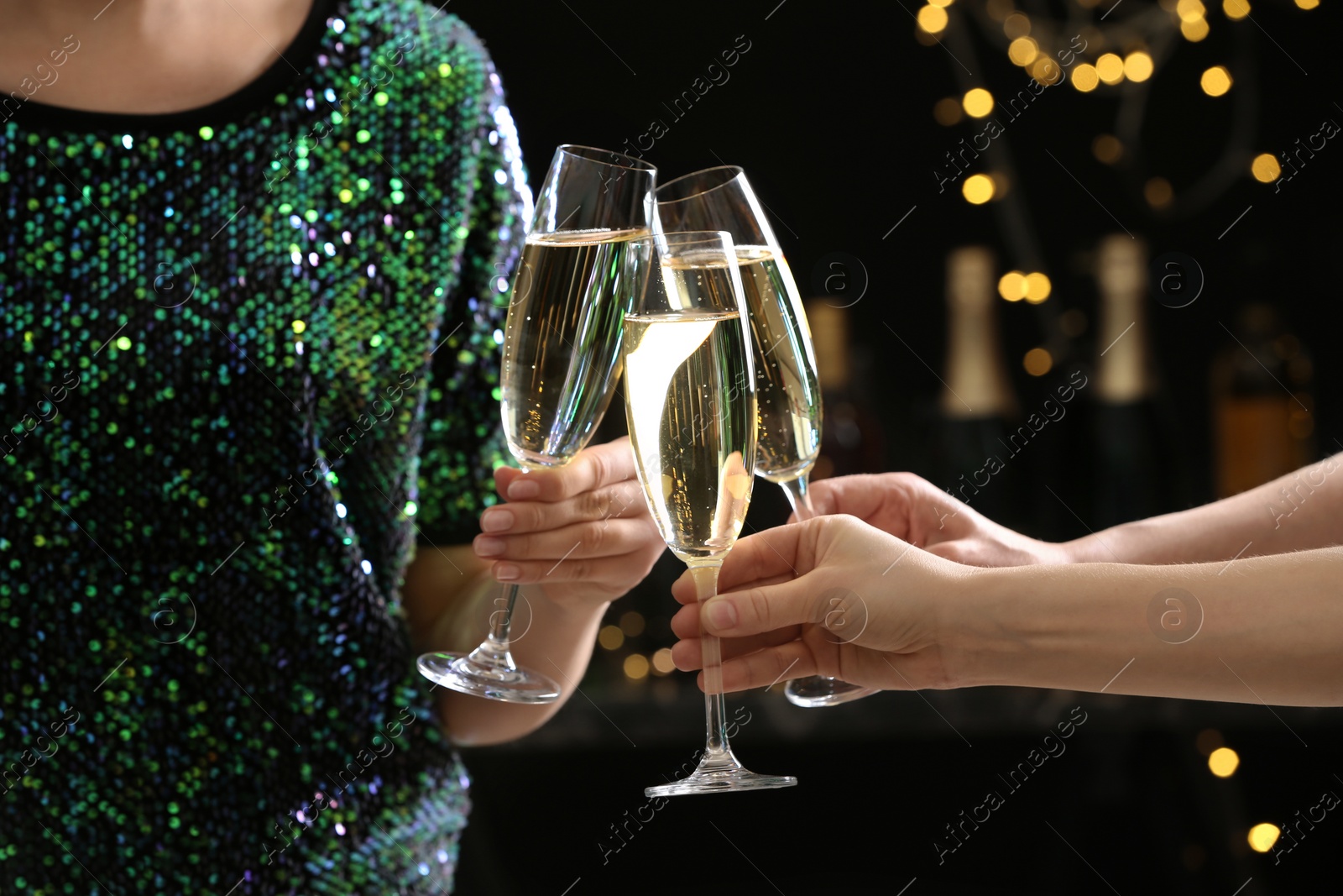 Photo of People clinking glasses of champagne on blurred background, closeup