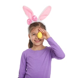 Photo of Little girl in bunny ears headband holding Easter egg near eye on white background