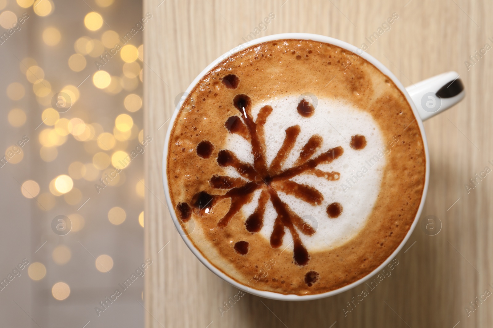 Photo of Cup of aromatic coffee on wooden table against blurred lights, top view