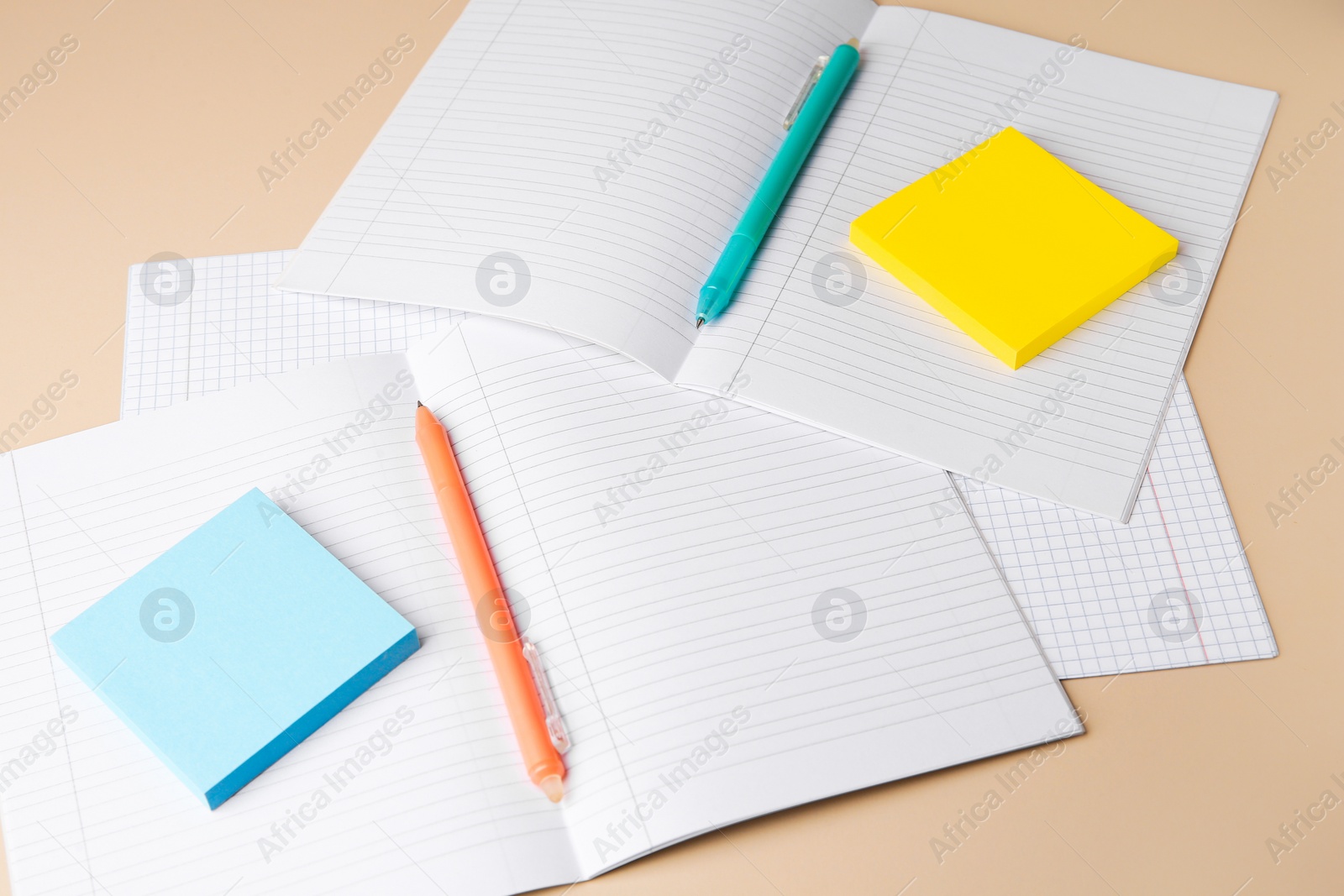 Photo of Copybooks with erasable pens and paper notes on beige background
