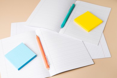 Photo of Copybooks with erasable pens and paper notes on beige background