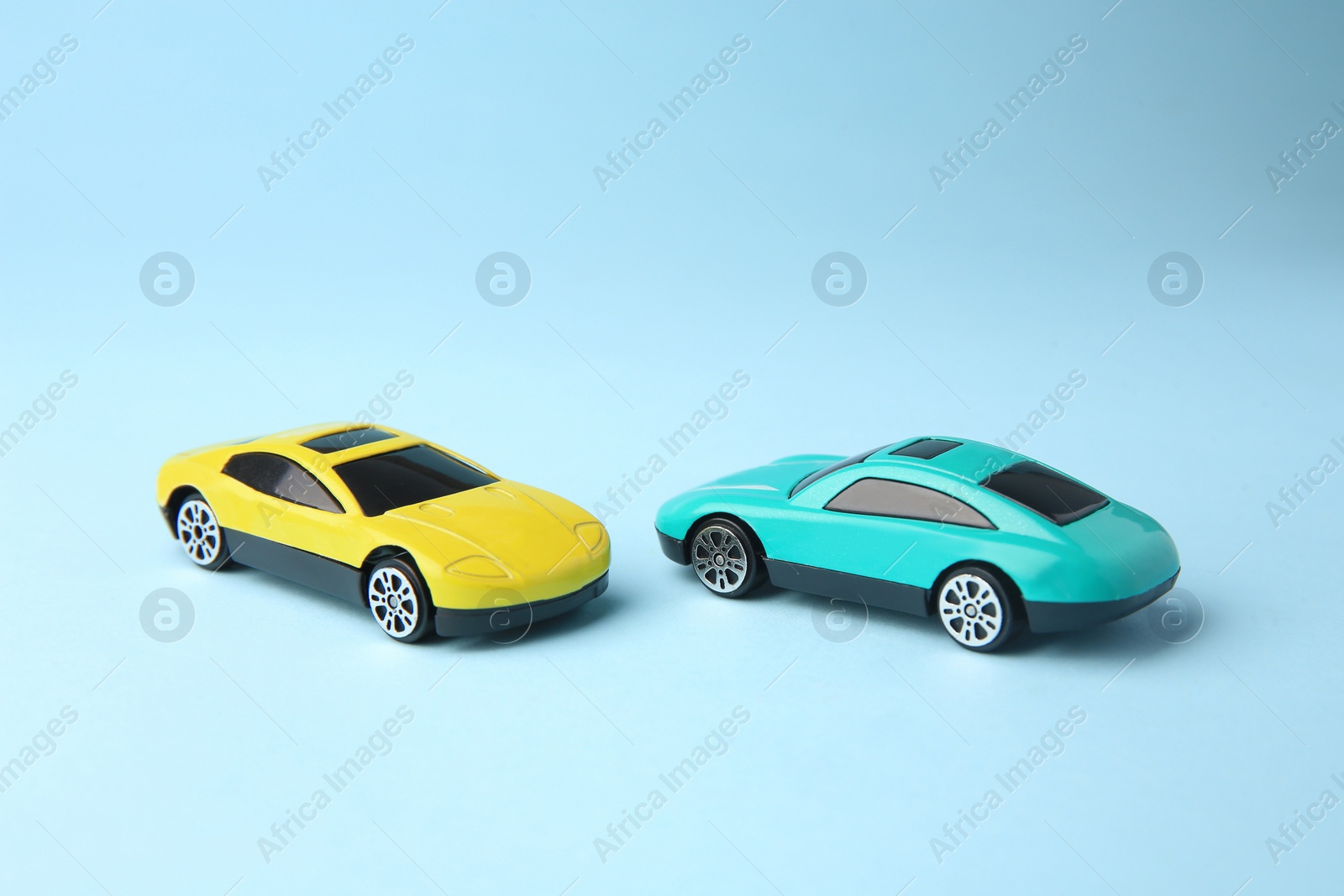 Photo of Two bright cars on light blue background. Children`s toys