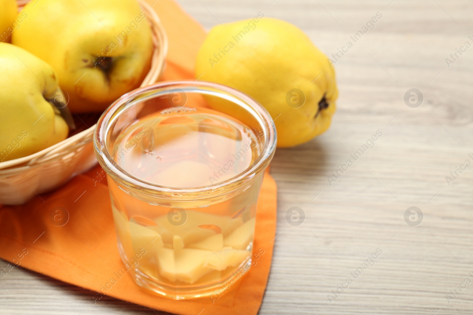 Photo of Delicious quince drink in glass and fresh fruits on wooden table, closeup. Space for text