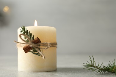 Burning candle with pinecone scent on light grey table, closeup. Space for text