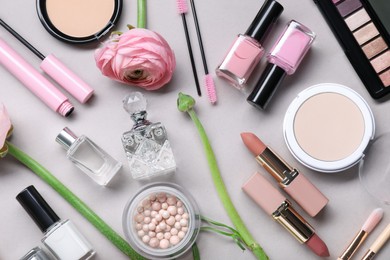 Flat lay composition with different makeup products and beautiful spring flowers on gray background