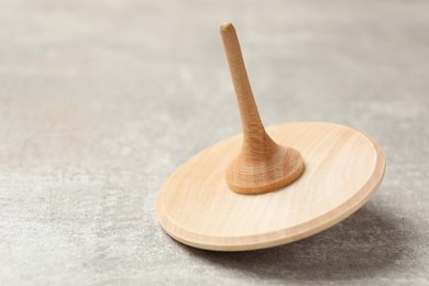 Wooden spinning top on grey textured background, closeup. Space for text