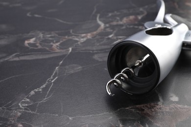 Photo of One wing corkscrew on black marble table, closeup. Space for text