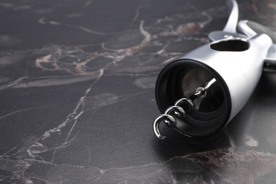 One wing corkscrew on black marble table, closeup. Space for text