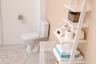 Toilet paper rolls on shelving unit in bathroom. Space for text