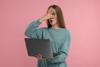 Photo of Embarrassed woman with laptop covering face on pink background