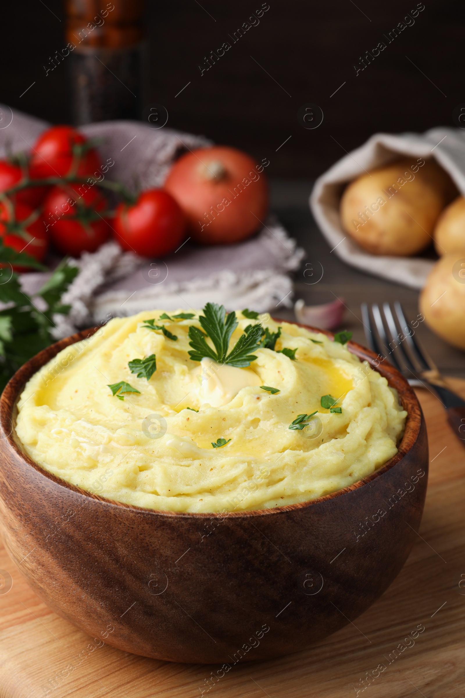 Photo of Bowl of freshly cooked mashed potatoes with parsley served on wooden table