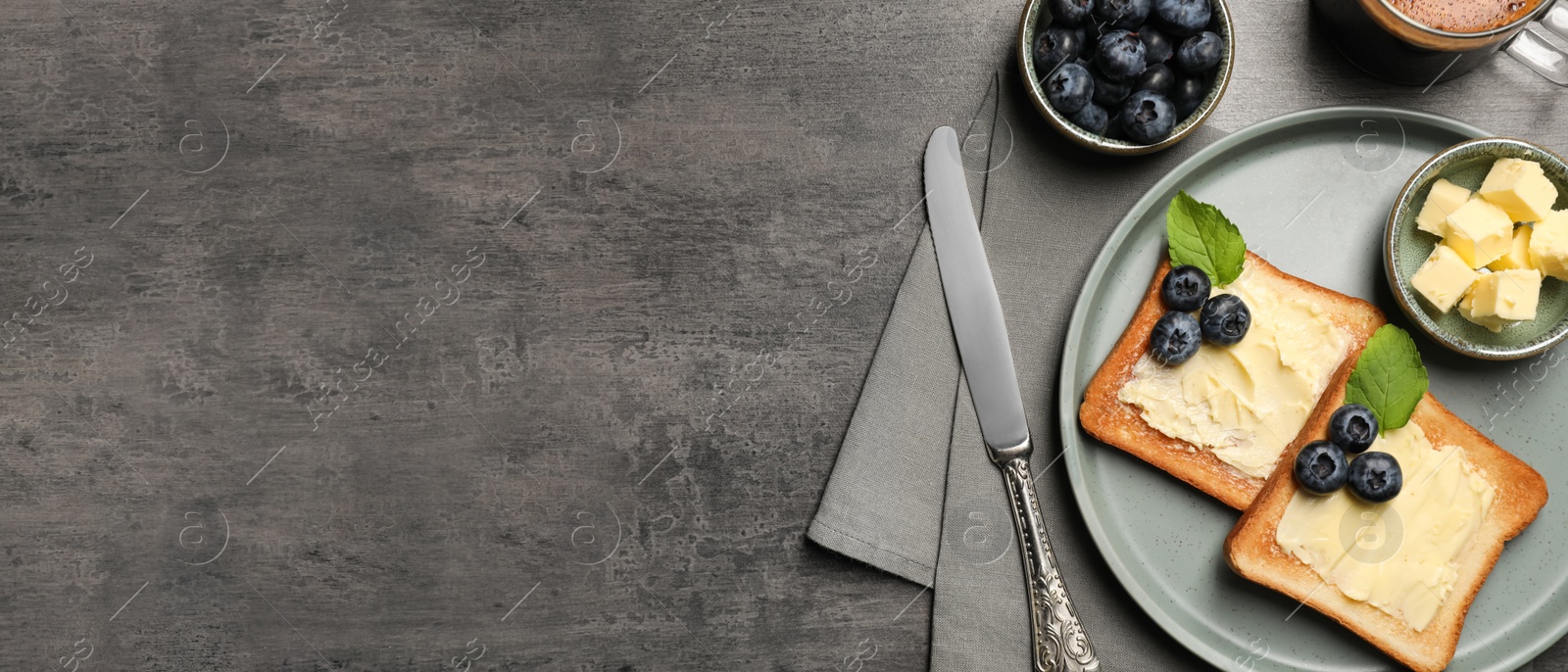 Image of Plate of delicious toasts served with butter, blueberries on grey table, flat lay with space for text. Banner design