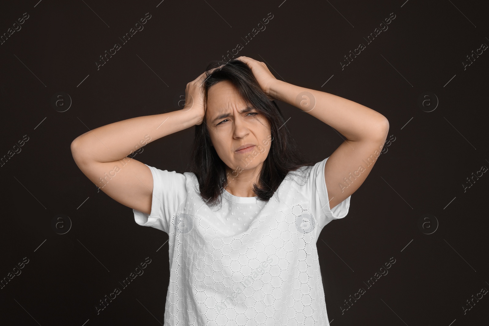 Photo of Mature woman suffering from headache on dark brown background