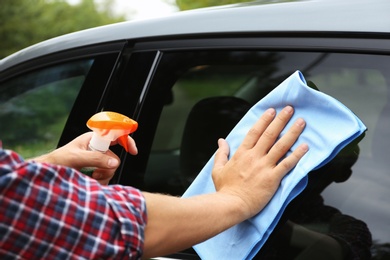 Photo of Man washing car window with rag outdoors, closeup