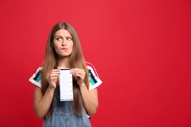 Photo of Portrait of emotional young woman with lottery ticket on red background, space for text