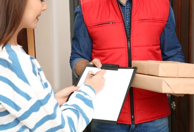 Woman receiving parcels from delivery service courier indoors, closeup