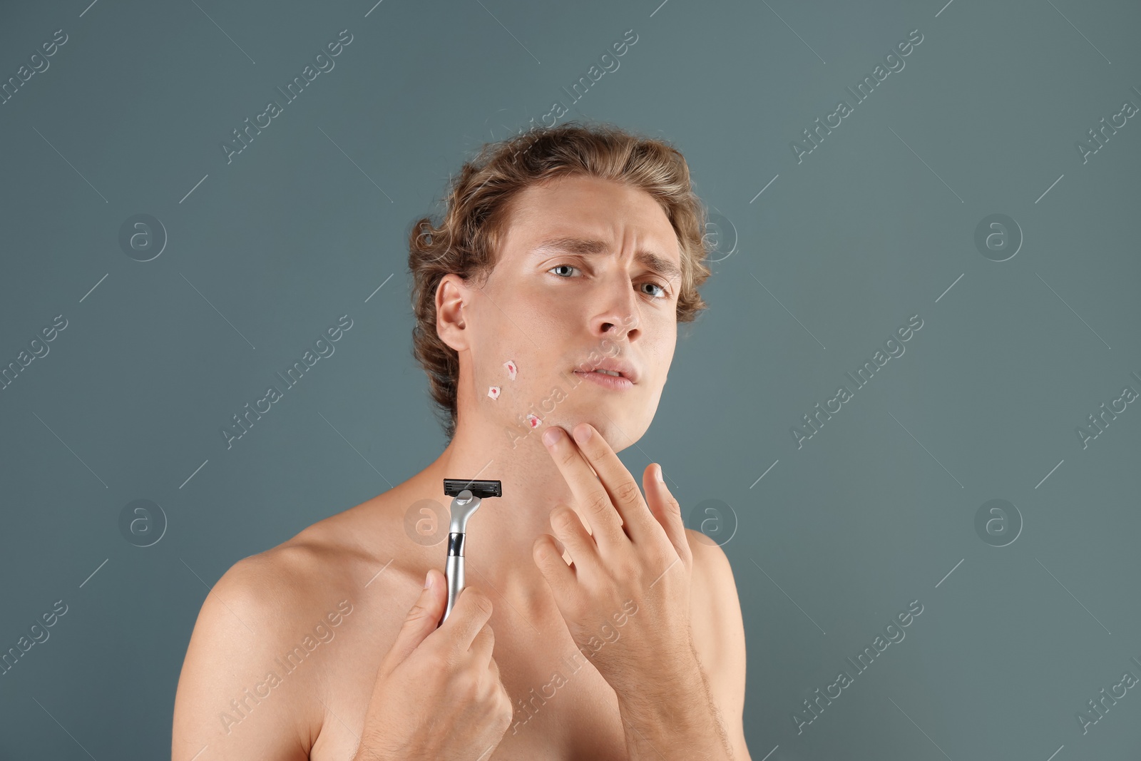 Photo of Young man with face hurt while shaving on gray background