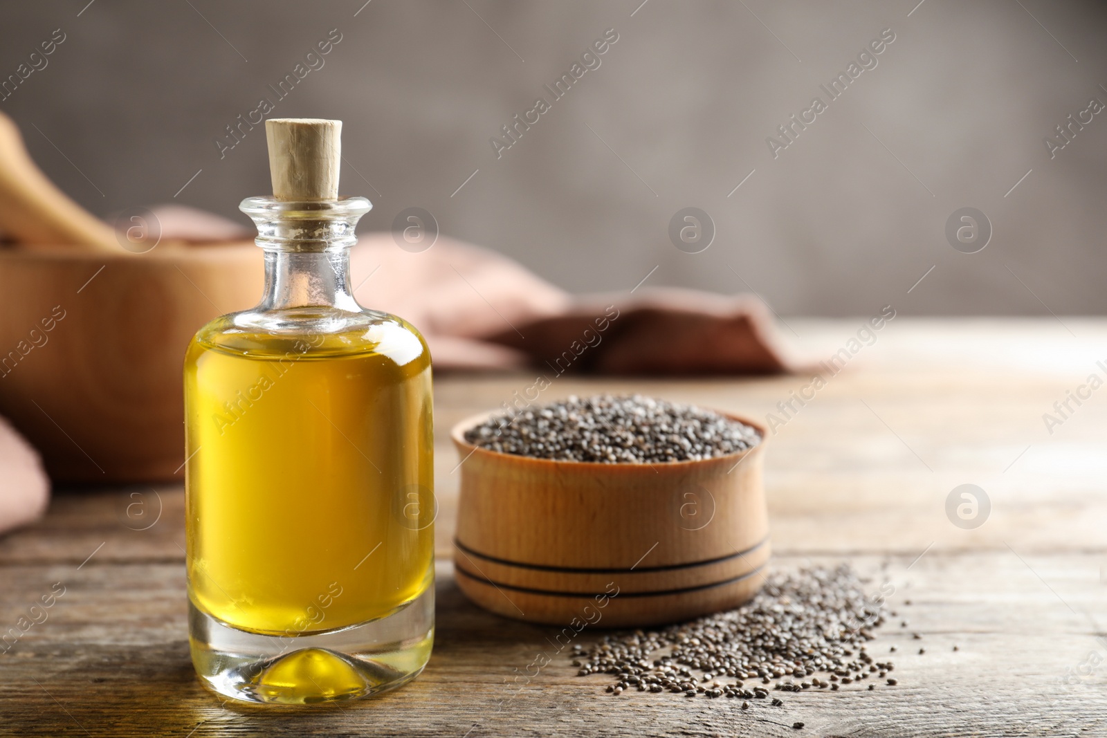 Photo of Bottle of chia oil and bowl with seeds on table. Space for text