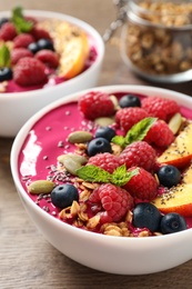 Photo of Delicious acai smoothie with granola and berries on wooden table