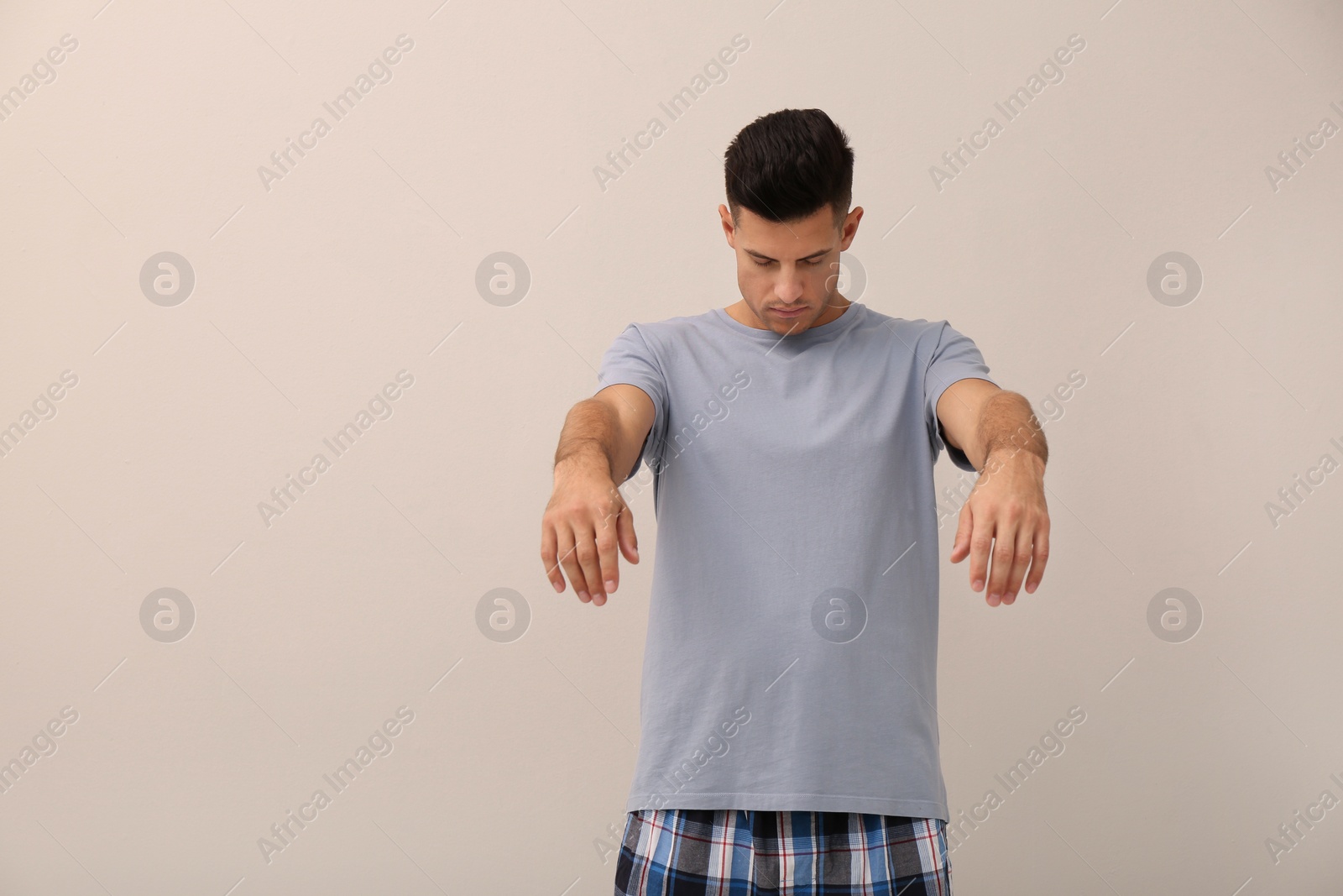 Photo of Somnambulist wearing pajamas on beige background. Sleepwalking