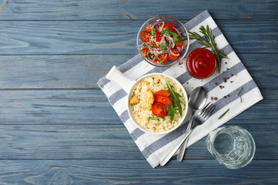 Photo of Delicious chicken risotto served on blue wooden table, flat lay. Space for text