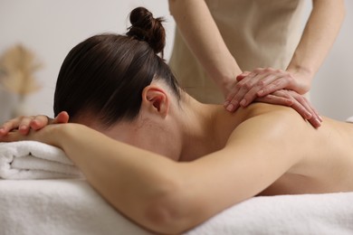 Photo of Woman receiving back massage on couch in spa salon