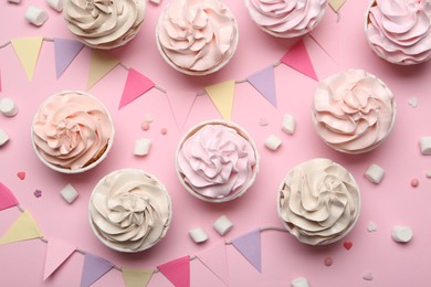 Delicious birthday cupcakes, bunting flags, marshmallows and sprinkles on pink background, flat lay