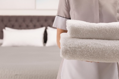 Maid with fresh towels in hotel room, closeup