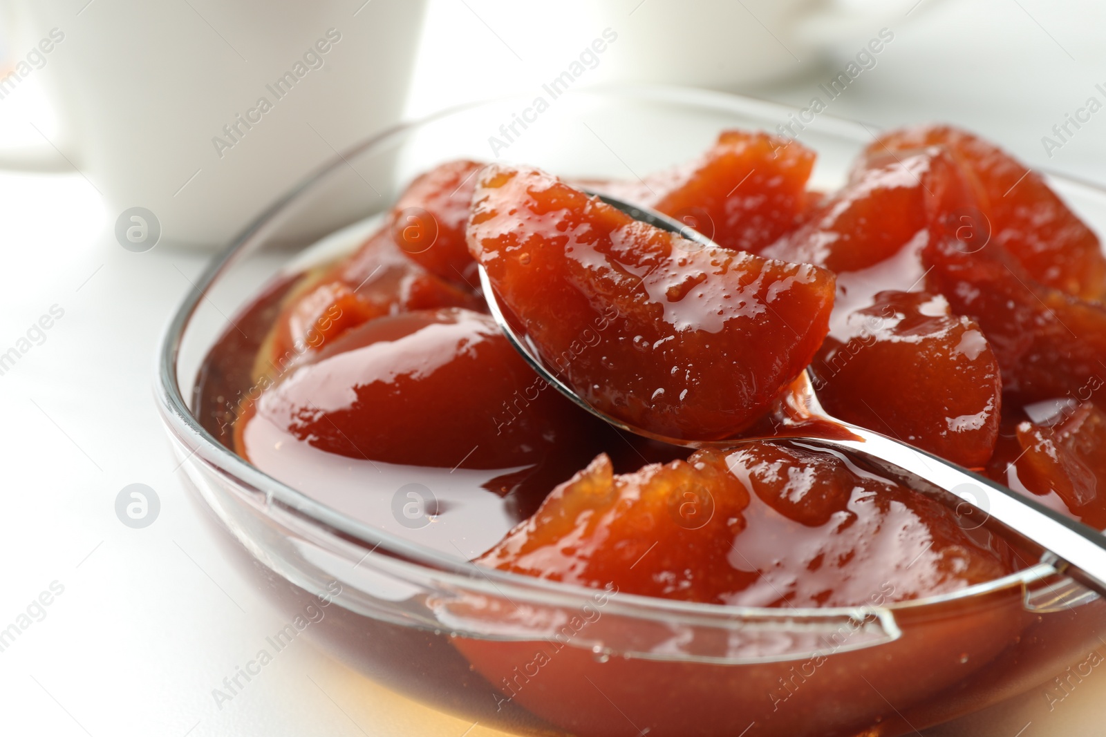 Photo of Quince jam in glass bowl on white table, closeup
