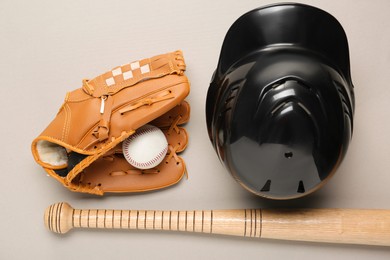 Photo of Baseball glove, bat, ball and batting helmet on light grey background, flat lay