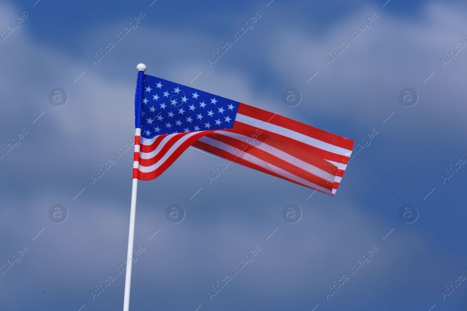Photo of Small American flag against cloudy blue sky