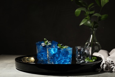 Photo of Tray with glasses of jelly on table against dark background