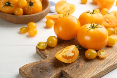 Photo of Ripe yellow tomatoes on white wooden table, closeup